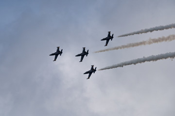 Low angle view of airshow in cloudy sky