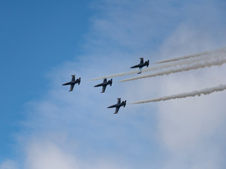 Low angle view of airshow in cloudy sky