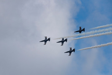 Low angle view of airshow in cloudy sky