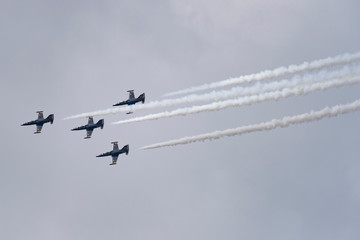 Low angle view of airshow in cloudy sky