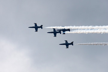 Low angle view of airshow in cloudy sky