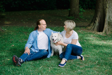 Fototapeta premium Adult couple sitting on the grass with a white hash