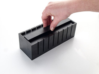 Mano apretando el contenido de una caja de corte para sushis en un fondo blanco