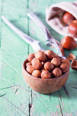Hazelnuts in wooden bowl on old cyan green table. Copy space.