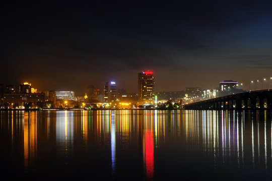 Panoramic view of the city at night. Cityscape near the river at night with reflection in the water.