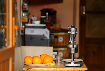 ripe bright oranges on the table in the kitchen next to the chrome juicer