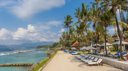 Sunbeds under palm trees at the Candidasa coast of Bali
