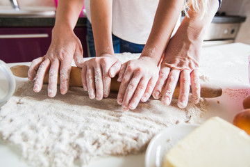 Obraz na płótnie Canvas Hands Of Mother And Daughter Rolling Pizza Dough With Rolling Pin