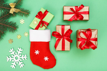 Santa's boot, gift boxes and fir tree branch on green background