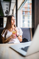 Beautiful young woman with lemonade and laptop in summer cafe