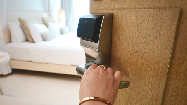 Female&rsquo;s hand with accessories opening hotel room. Housekeeper or room service worker opening door to appartment.