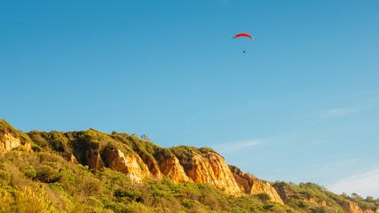 One man gliding using a parachute on the background of the blue sky