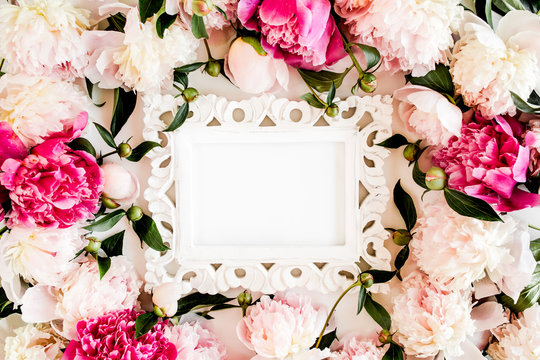 Carved, white frame decorated of beautiful pink peonies on white background. Flat lay, top view. Valentine's background. Floral frame. Peony texture.