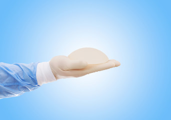 Silicone breast implant on hands. Doctor tries on silicone breasts.