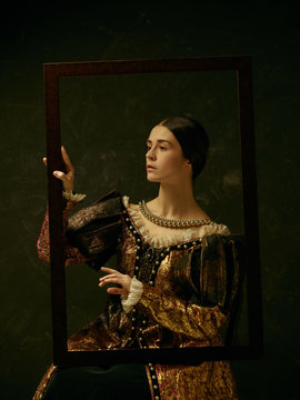 Portrait of a girl wearing a princess or countess dress over dark studio. portrait through picture frame