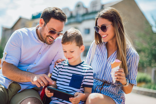 Smiling parents and little boy with tablet pc outdoor