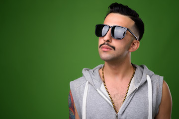 Young handsome Iranian man with mustache against green backgroun