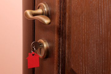 The concept of buying a home. Keys with keychain house in the door lock close-up