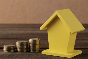 The concept of buying a home. Yellow decorative house and money on a brown background with a place for an inscription.
