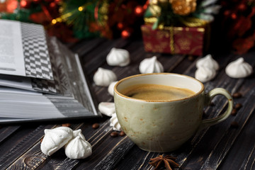 A cup of coffee with meringues and a book on a wooden background, new year's decor