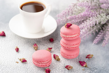 Pink macaroons with dried flower buds and cup of coffee. Pastel colored.