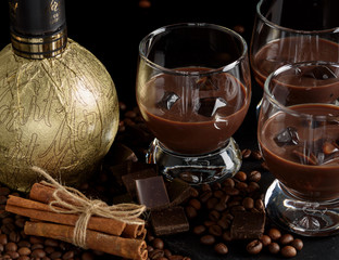 Chocolate, coffee, creamy liqueur, cocktail with coffee beans, chocolate and cinnamon. On a black background. Christmas alcoholic drink