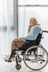 thoughtful sad senior man sitting in wheelchair in nursing home
