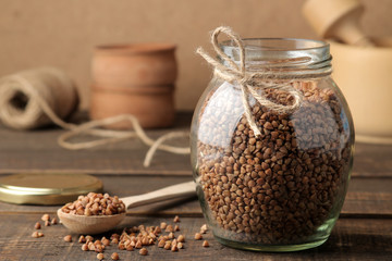 Dry buckwheat groats in a glass jar in the foreground on a wooden brown table. cereals. healthy food. porridge.