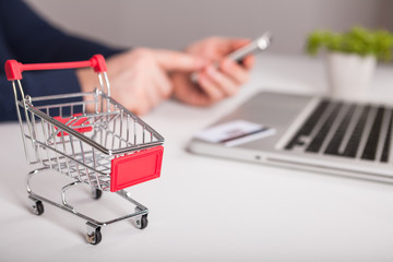  Bank card nearby a laptop and mini shopping cart on white background top view.