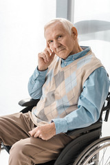 thoughtful sad senior man sitting in wheelchair in nursing home