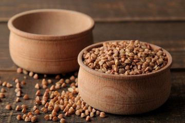 Dry buckwheat groats in a wooden bowl on a wooden brown table. cereals. healthy food. porridge.