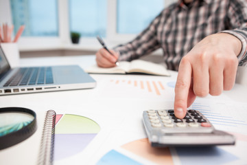 Businessman analyzing business graphs with magnifying glass