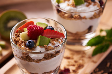 Two glasses of delicious yogurt and fruits ion wooden table