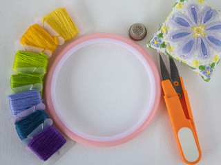 accessories for embroidery. white canvas. copy space. scissors, floss, hoops.