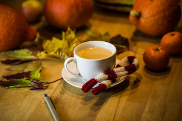 Coffee cup with pen, in the background pumpkin, leaves, apples