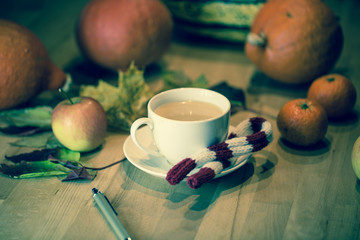 Coffee cup with pen, in the background pumpkin, leaves, apples