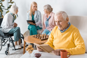 senior man reading book while female doctor examining senior women