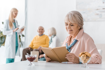 Obraz premium senior woman reading book while female doctor examining people