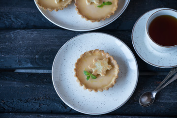 a homemade dessert of lemon tartlets rustic style, dark wooden backdrop