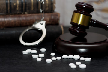 Judge's gavel with handcuffs, drugs on wooden table