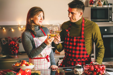 Couple celebrating Christmas in the kitchen and drink wine
