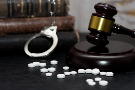 Judge's gavel with handcuffs, drugs on wooden table