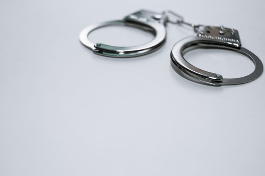 Handcuffs on a white background in the upper left corner of the frame.