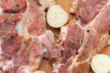 Raw pork meat with spices and onion on wooden cutting board