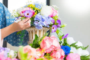 young women business owner florist making or Arranging Artificial flowers vest in her shop, craft and hand made concept