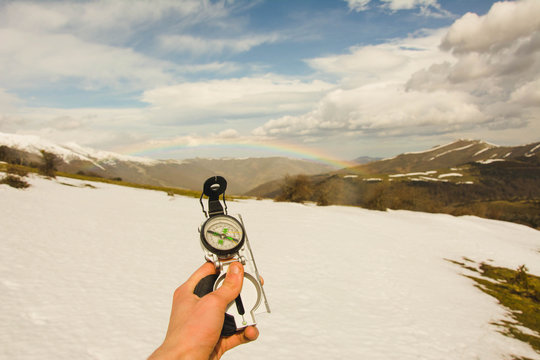 Woman with compass in mountains with rainbow