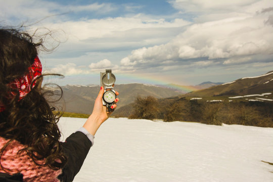 Woman with compass in mountains with rainbow