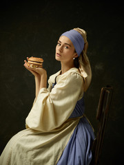 Medieval Woman in Historical Costume Wearing Corset Dress and Bonnet with burger. Beautiful peasant...