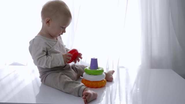 baby educational, infant boy is played with toy tower in bright room close-up