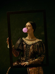 Portrait of a girl wearing a princess or countess dress over dark studio. portrait through picture...